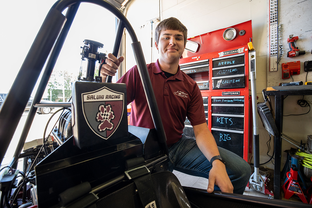 SIU student sits next to Saluki Racing car